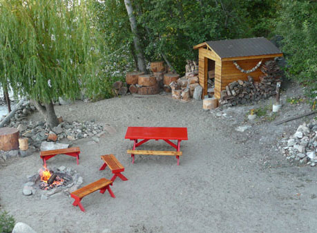 Sandy beach with table, seating, and firewood
